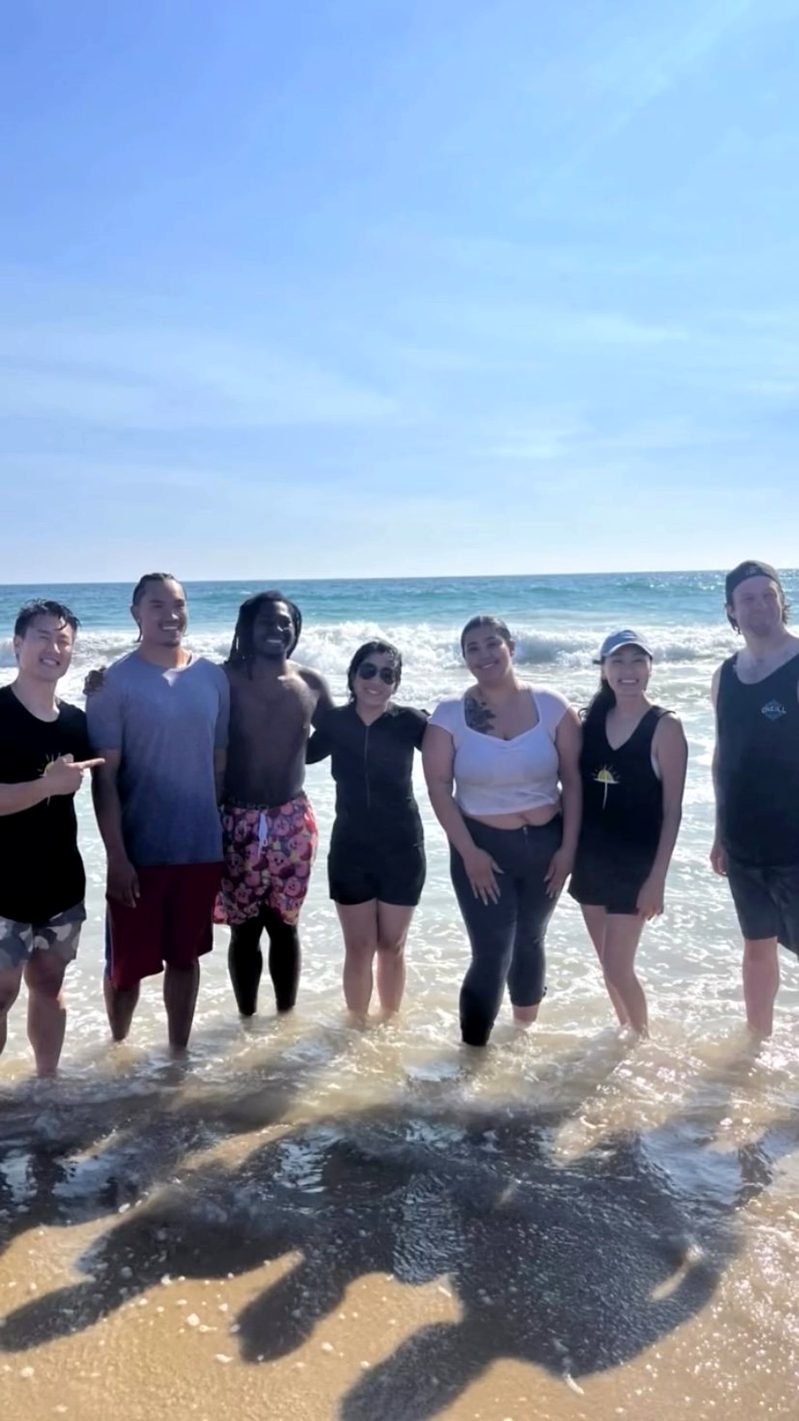 A group standing together in the shallow water at the beach
