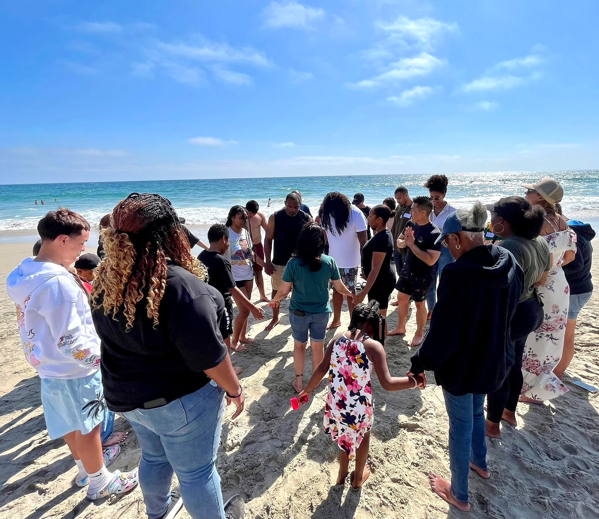 People holding hands in a circle on the beach