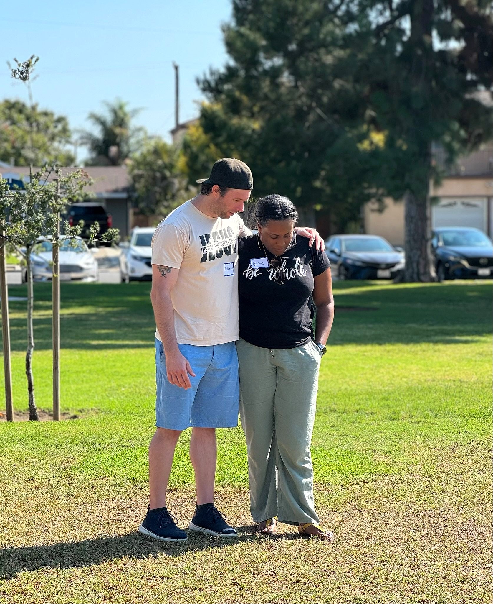 A man and woman standing arm in arm in a park