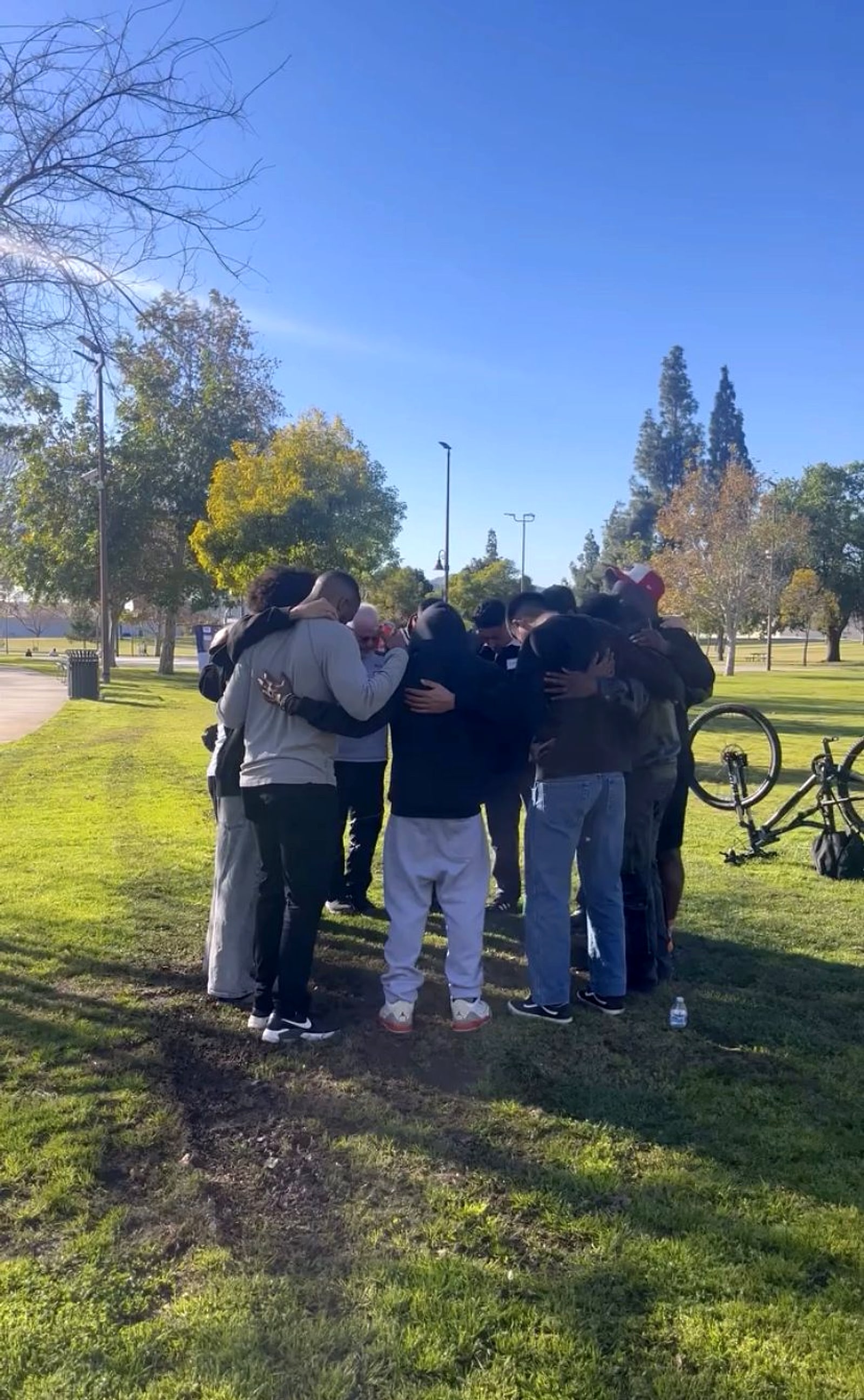 A small group huddled in prayer in a park