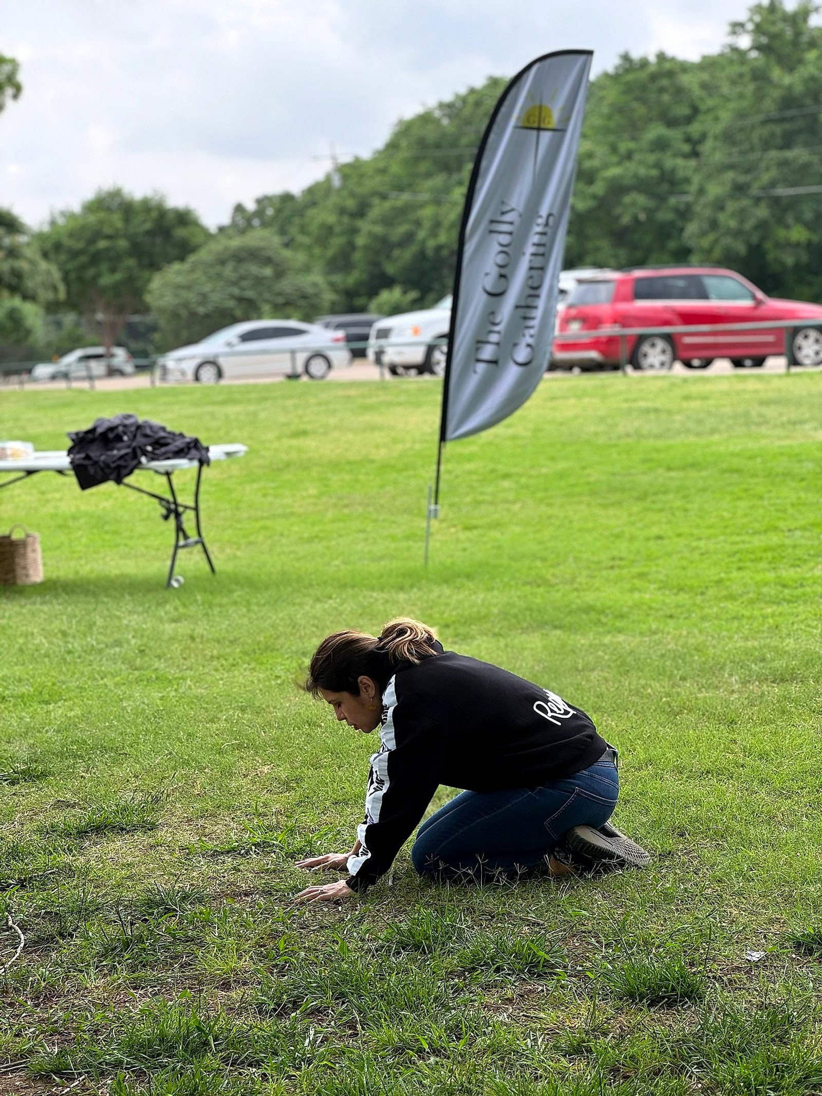 Someone kneeling alone in prayer on a green field