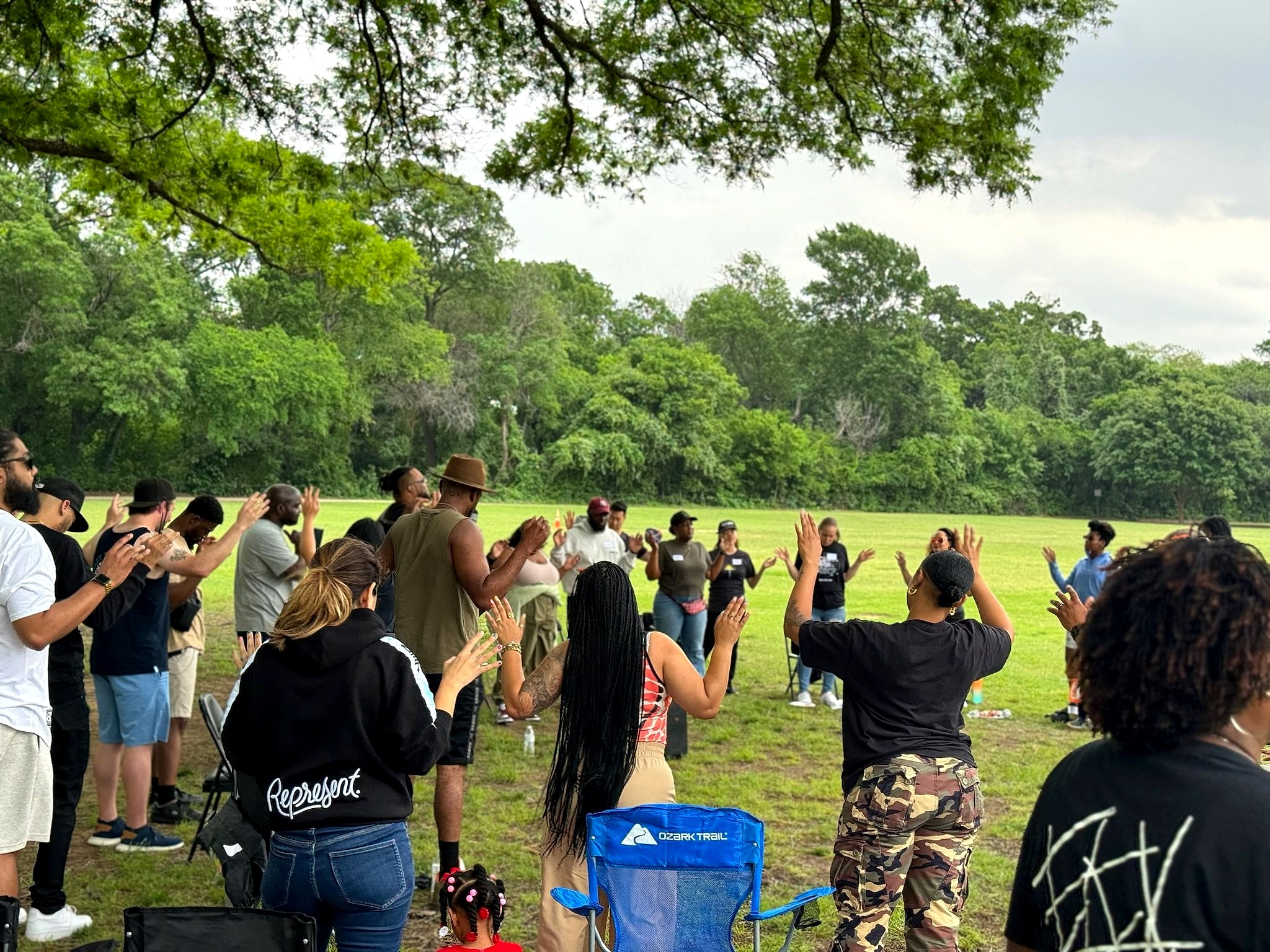 A big circle of people praying together on the grass