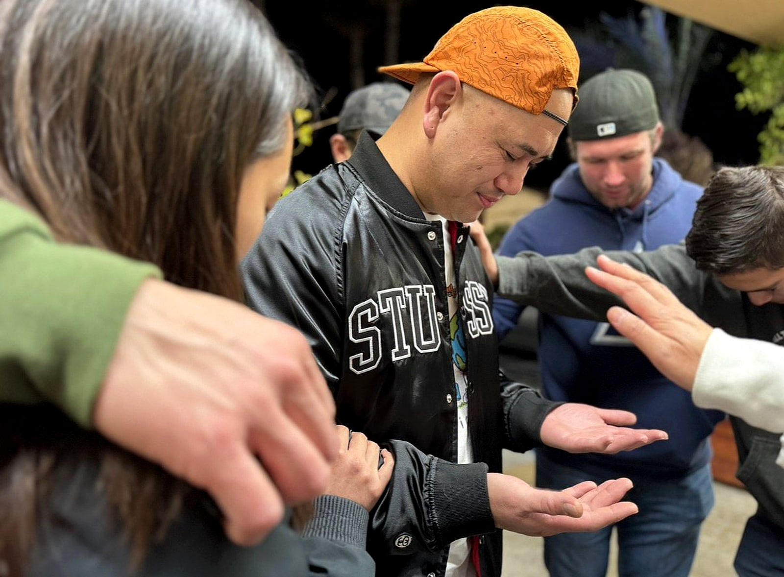 Men praying with open hands and hands on shoulders