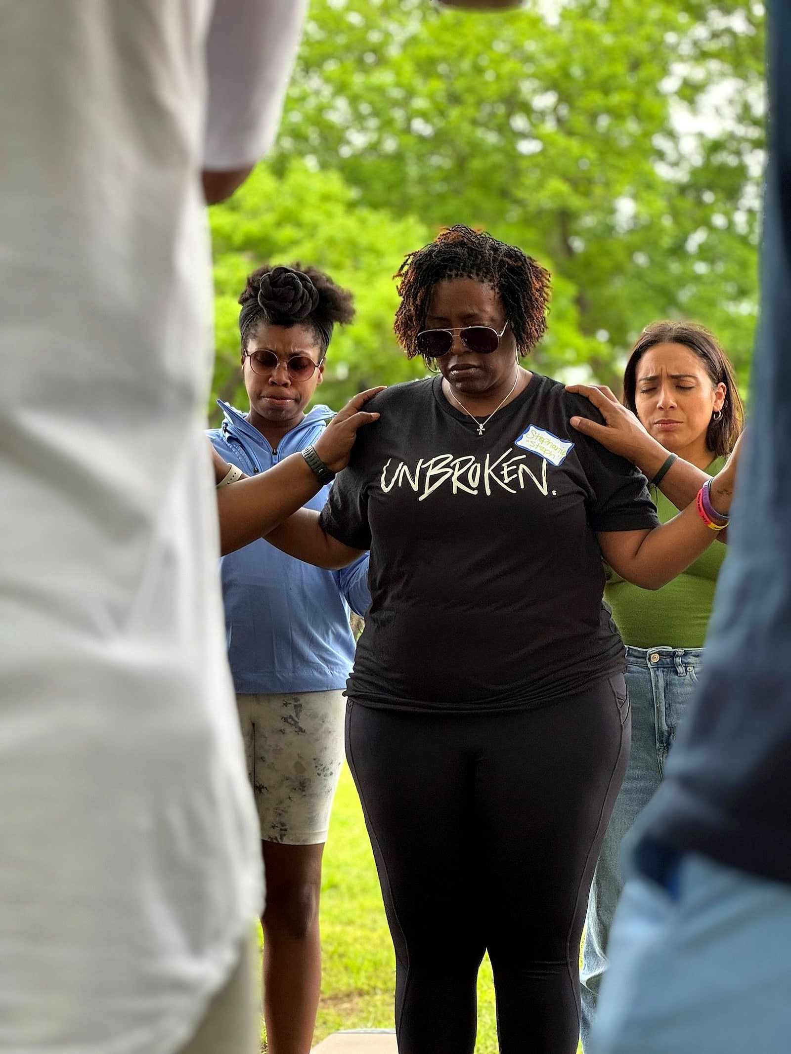 Friends laying hands on a woman as they pray